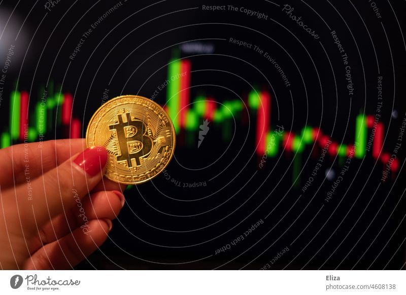 Woman holding a bitcoin coin. In the background are trading candles on a screen. Cryptocurrencies. bit coin Cryptocurrency price crypt Money trade