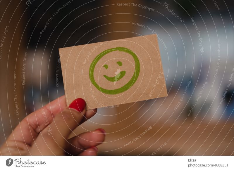 Woman holding sign on which positive smiling smiley is painted Smiley Positive Good smilingly Optimism Joy Contentment Green appraisal Moody good mood Emoticon