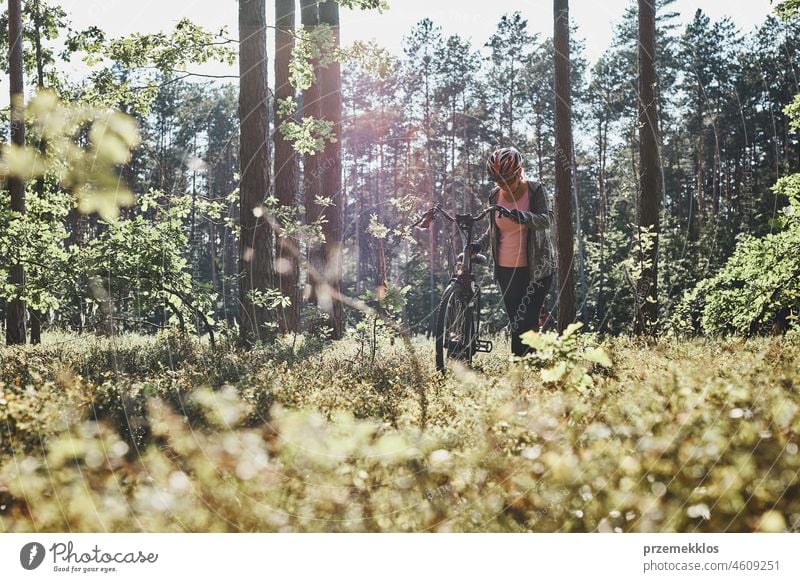 Active woman cycling on forest road. Female riding bicycle off-road route on summer vacation day trip adventure biking recreation travel bike action activity