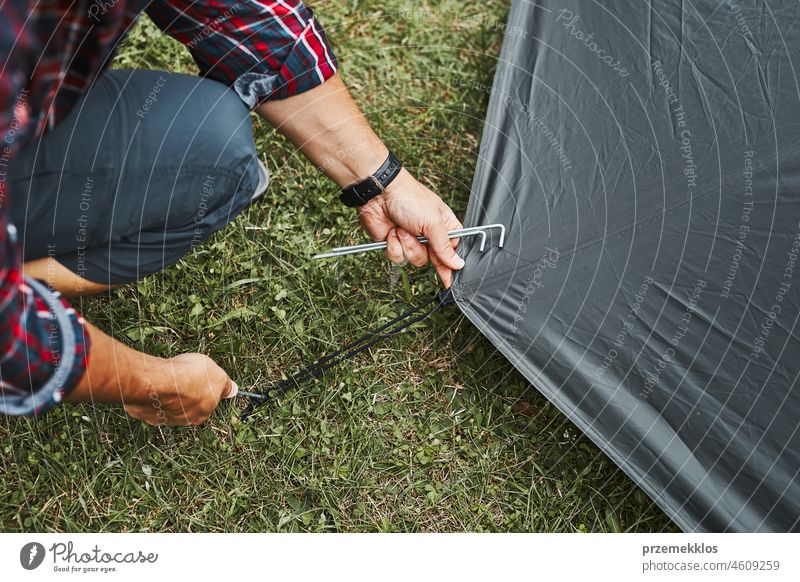 Man putting up a tent at camping during summer vacation. Preparing campsite to rest and relax. Spending vacations outdoors close to nature adventure trip