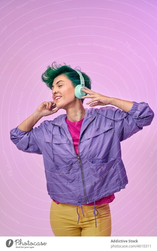 Woman in retro wear listening to music woman headphones meloman style millennial 80s fashion design song audio studio green hair female model short hair