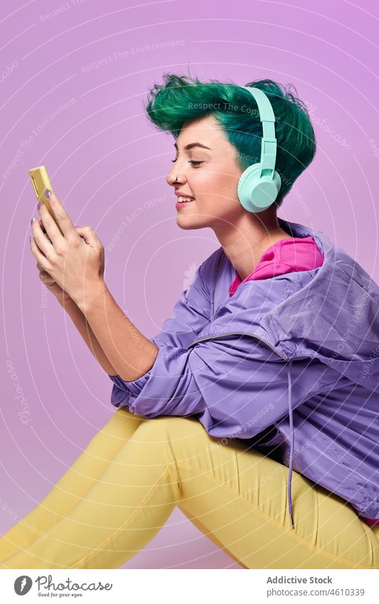 Millennial woman with headphones browsing smartphone social media meloman style millennial 80s online fashion design retro music studio green hair female model