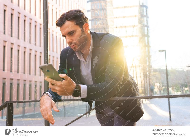 Businessman browsing smartphone while leaning on railing entrepreneur online formal street city business handrail barrier lean on urban male elegant businessman