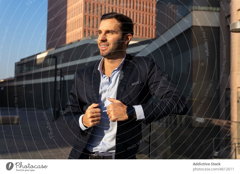 Smiling businessman man in suit on sunny street entrepreneur formal smile city wait urban male elegant appearance brunet glass fence beard lean well dressed