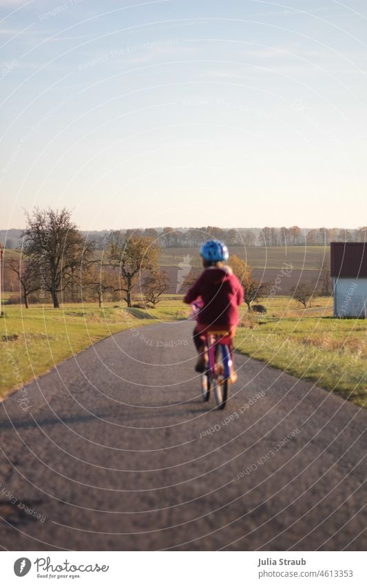 fast as the wind, she passes by on her bike Cycling Bicycle Children's bike Wheel Cyclist Helmet off the beaten track tarred trees Fruit trees Arable land acre