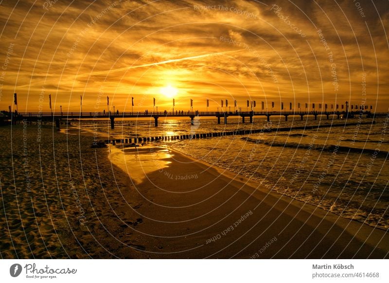 The pier in Zingst at sunset bathed in orange light Pier evening hour attraction summer sea water vacation recreation beach calm Baltic Sea sand coast tourism