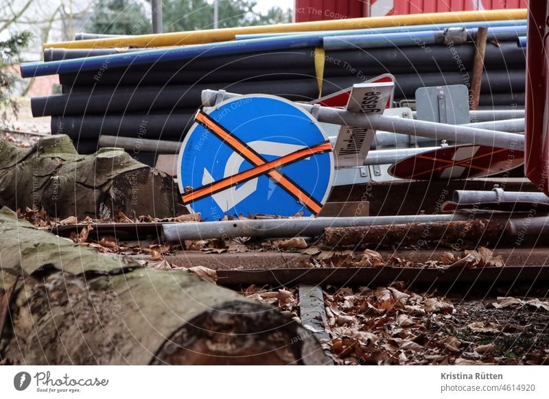 an invalid left turn sign lies on the ground of a construction site with other traffic signs, tree trunks and pipes left turn-off Traffic signs street sign