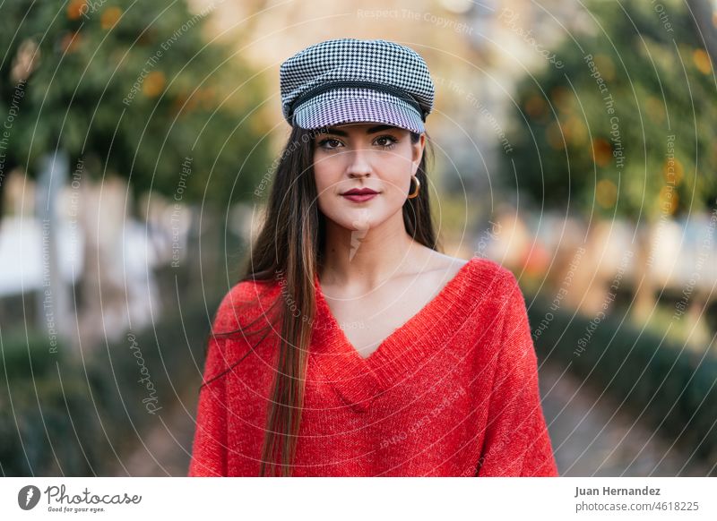 Frontal portrait of a beautiful woman in red sweater and black and white plaid cap frontal nice model lady horizontal looking at camera posing confidence