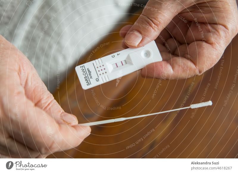 Senior woman taking Rapid Antigen test for self-diagnostic SARS-CoV-2, Covid-19, Coronavirus at home. Close up positive test result in hands. aged antigen