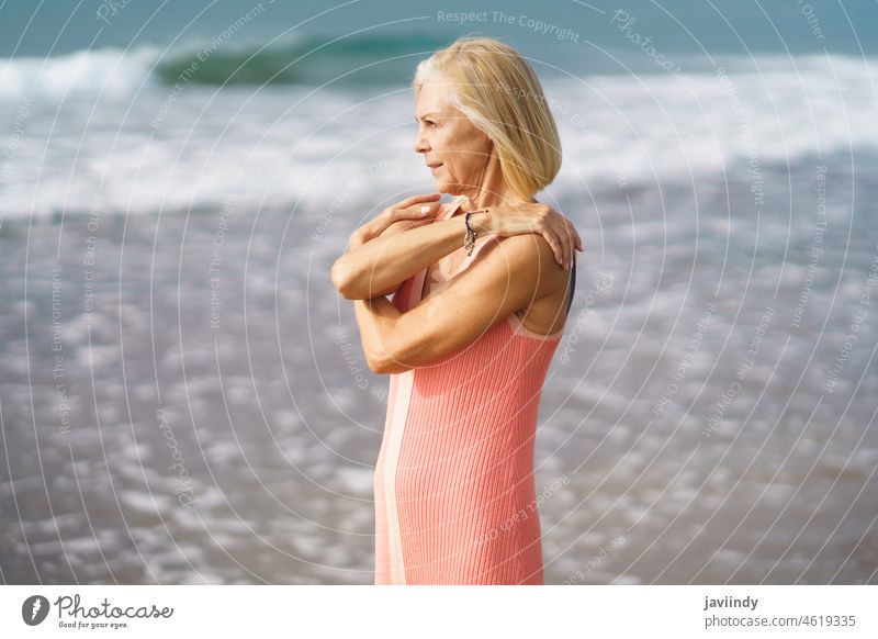 Mature woman on shore of a beach. Elderly female enjoying her retirement at a seaside retreat. mature senior old person lifestyle happy holiday relaxing sand