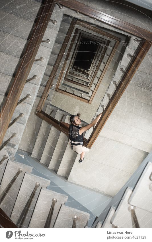 It’s a dangerous move by a gorgeous brunette girl to lean towards an endless hole in this vintage corridor. Fashion model dressed in a fancy outfit looking into a camera. The look and the situation is giving chills.