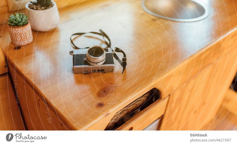 Old analog photo camera on the table of a camper van ready to start the road trip wooden table campervan vacation travel memory fun adventure summer american