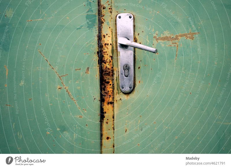 Old defective door handle in a rusty green steel door on a former factory site in the Margaretenhütte district of Giessen on the river Lahn in the state of Hesse, Germany