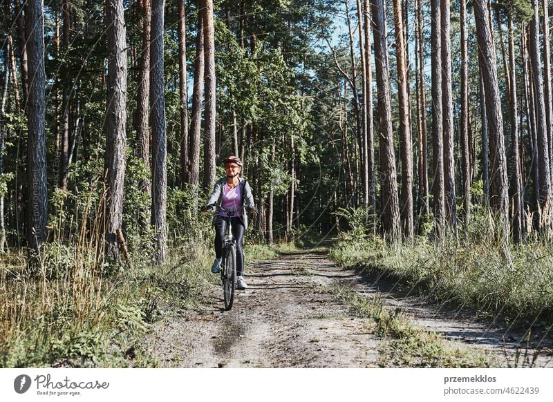 Active woman cycling on forest road. Female riding bicycle off-road route on summer vacation day trip adventure biking recreation travel bike action activity