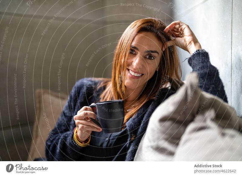 Happy woman with coffee sitting in office hot drink break couch portrait workplace worker entrepreneur style modern positive lady professional workspace female