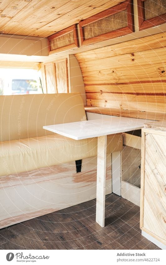 Interior of camping van with sofa and table trailer bed interior road trip cabinet caravan accommodation living wooden transport journey parked summer