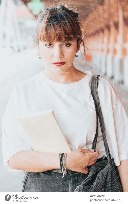 Young woman on white shirt holding a book at the train station, reading everywhere people, book hobby fan. Waiting for the train to come, killing free time activities and habits