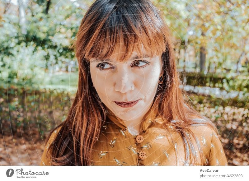 Portrait of a young red head naughty woman looking away from camera while wearing modern and trendy dress. Self confidence and womanhood attitude concepts, feminism and confident future.