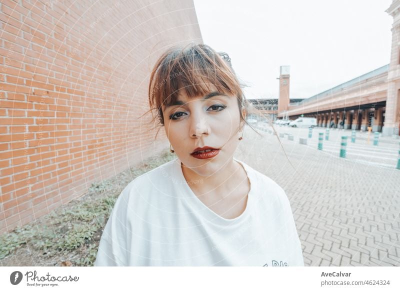 Portrait of a young arab african girl on serious hip hop youngster attitude looking serious and fun to camera on a white shirt with an urban background.Beauty young street life street artist at city