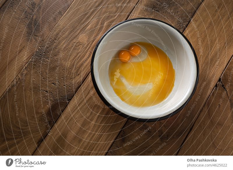 Raw broken for breakfast double yolk chicken egg smiling at you from metal bowl table prepare view top wood healthy cuisine ingredient fresh happy happiness