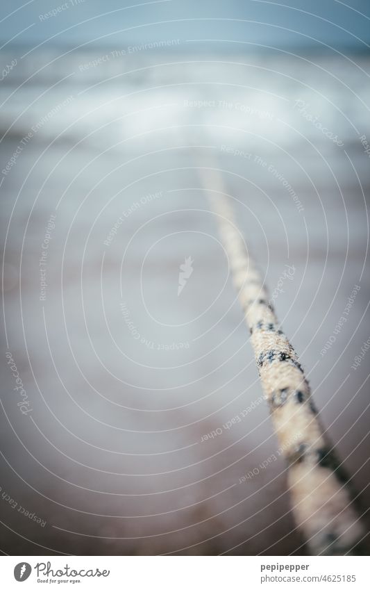 Rope that reaches into the water Dew Water Waves Ocean Maritime Deserted Beach Exterior shot Harbour Close-up Detail coast mooring rope Knot blurriness