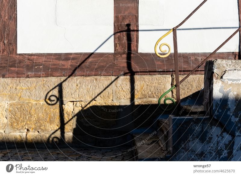 Staircase up staircase down | staircase railing and shadow in front of a half-timbered house Upstairs Banister handrail Stairs Front stairs Upward wrought-iron