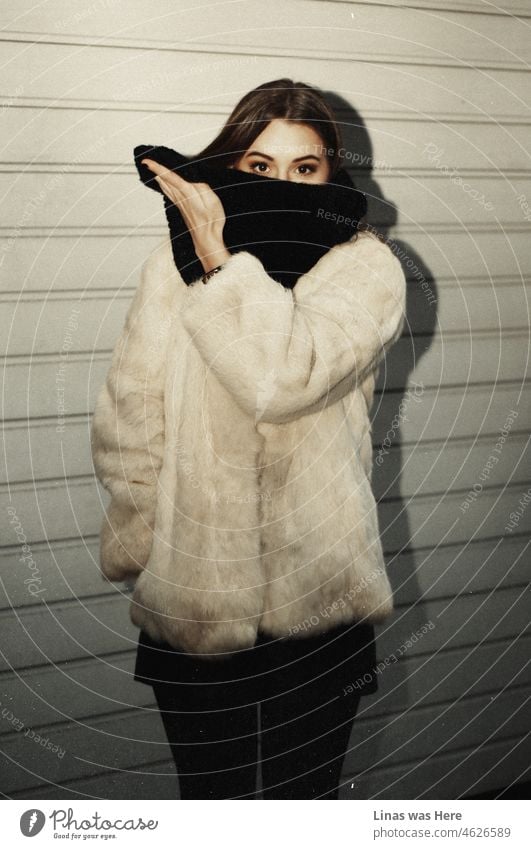 It’s still cold outside. Winter is freezing everything. Nevertheless, a gorgeous brunette girl is posing with a black scarf, comfy fake fur, and her natural beauty.