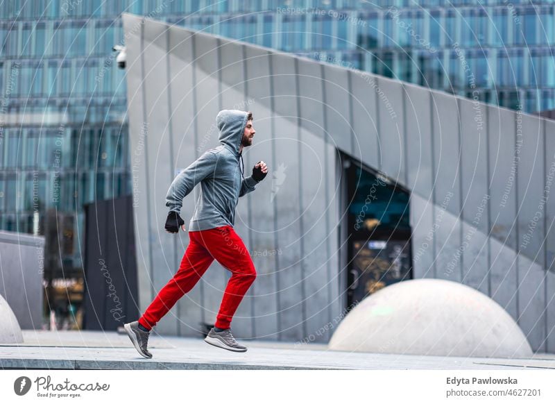 Young man running in the city people cold weather autumn sportsman strength motivation determination one person bodybuilding energy handsome confident guy