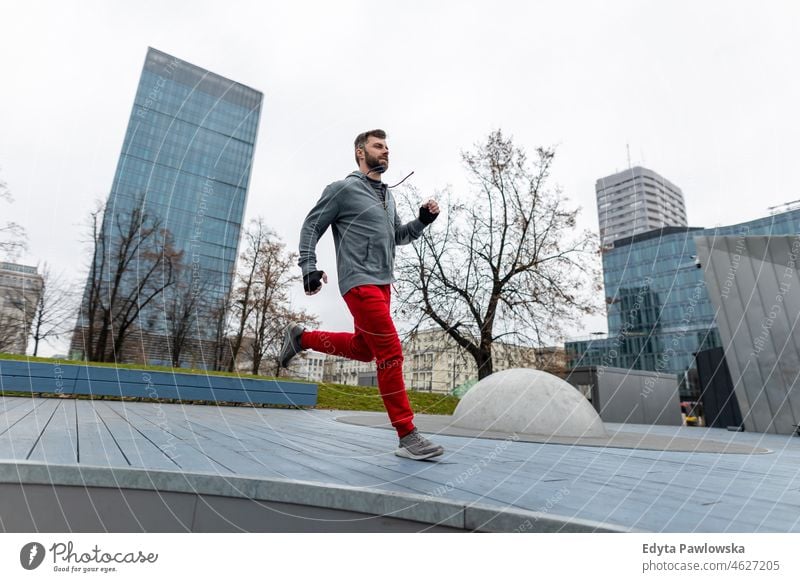 Young man running in the city people cold weather autumn sportsman strength motivation determination one person bodybuilding energy handsome confident guy