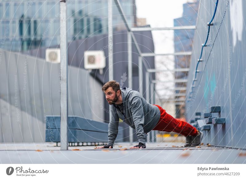 Young man exercising in urban setting people cold weather autumn sportsman strength motivation determination one person bodybuilding energy handsome confident