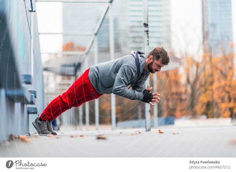 Young man exercising in urban setting people cold weather autumn sportsman strength motivation determination one person bodybuilding energy handsome confident