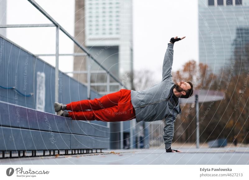 Young man exercising in urban setting people cold weather autumn sportsman strength motivation determination one person bodybuilding energy handsome confident