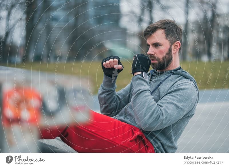 Young man exercising in urban setting people cold weather autumn sportsman strength motivation determination one person bodybuilding energy handsome confident