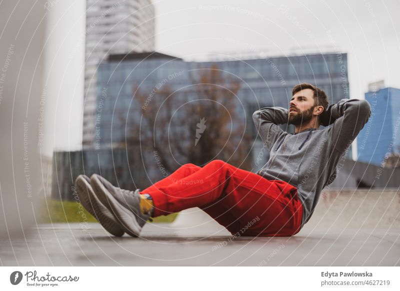 Young man exercising in urban setting people cold weather autumn sportsman strength motivation determination one person bodybuilding energy handsome confident