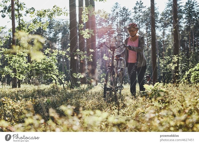 Active woman cycling on forest road. Female riding bicycle off-road route on summer vacation day trip adventure biking recreation travel bike action activity