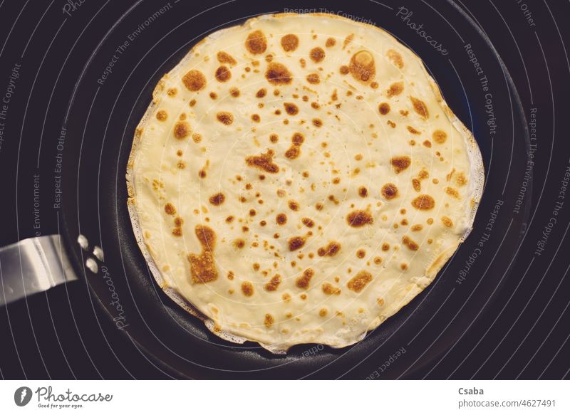 Cooking of crepe or thin pancake in a frying pan. Top view. griddlecake blini baking cooking top view dessert sweet food homemade plain flat French vegetarian