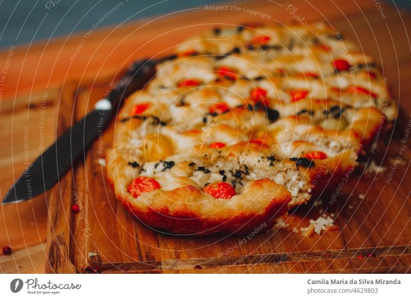 Homemade Italian Focaccia, with tomato and olive oil on a rustic wooden background. appetizer bake baked bakery black background bread cherry tomatoes closeup