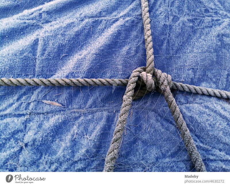 Boat stowage over an icy blue tarpaulin made of plastic in winter on a boat trailer in Oerlinghausen near Bielefeld on the Hermannsweg in the Teutoburg Forest in East Westphalia-Lippe