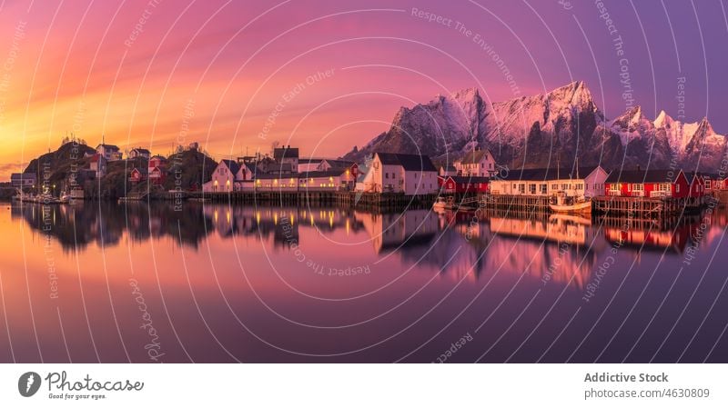 Fishing village near snowy mountains at sundown sea shore sunset house ridge cloudless sky winter lofoten Reine norway pink sky coast cottage landscape scenic