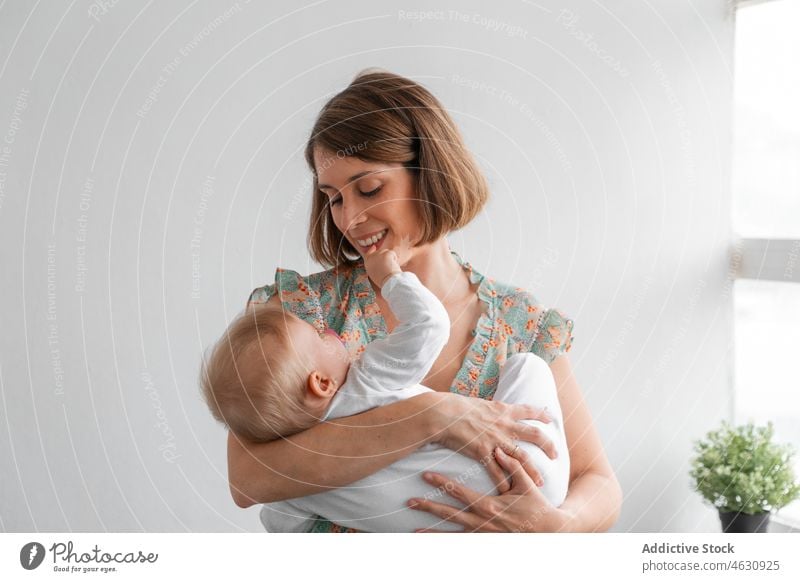 Mother holding baby in arms mother motherhood babyhood childcare home domestic love maternal bonding cute adorable innocent room little light at home flat