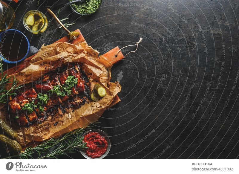 Fried ribs with BBQ sauce and various pickled vegetables fried bbq black kitchen rosemary wooden cutting board bowls cooking savory food home top view