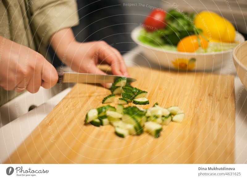 Woman cutting cucumbers preparing a salad - making vegan healthy meal vegetarian healthy food healthy eating healthy lifestyle homemade social gathering