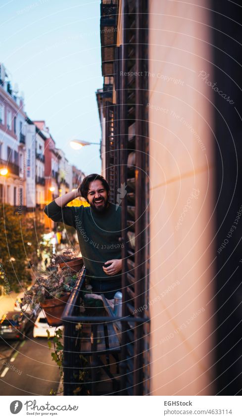 Happy casual young man laughing in the balcony on a typical Madrid building facade on a street happy vibes good center old person adult city spain outdoors view