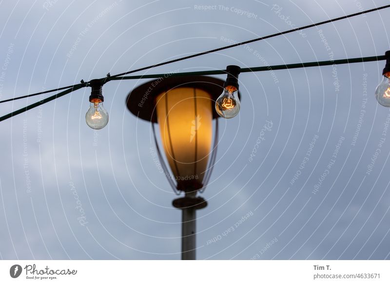 a chain of lights in front of an old lantern in Berlin Prater beer garden Lantern Beer garden Fairy lights Electric bulb Evening chestnut avenue Prenzlauer Berg