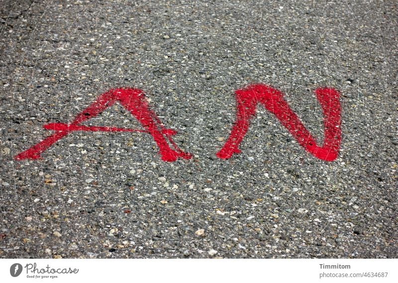 AN in red on Word Letters (alphabet) Characters Colour Red Asphalt Street Text Gray not off Deserted Clue Information