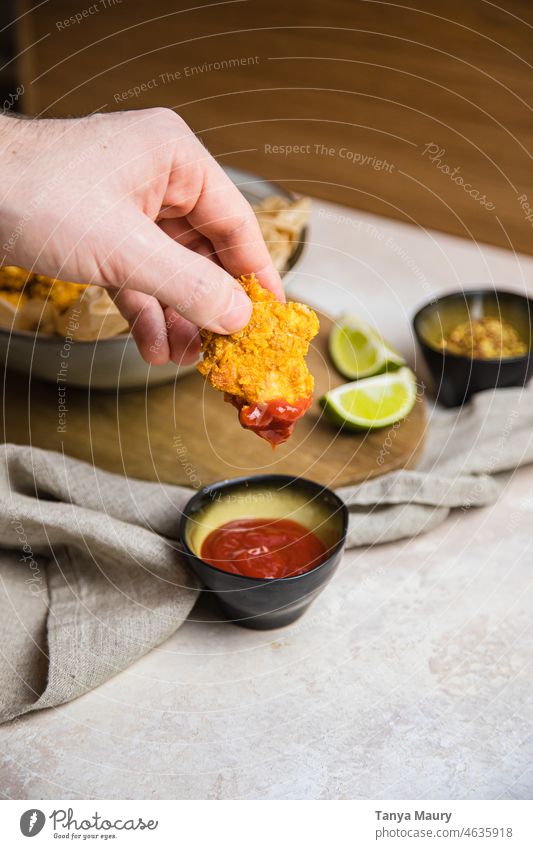 hand dipping a vegan fried nuggets in ketchup Frying Lunch Cooking Gourmet tofu vegan protein Fresh Fried chicken rustic Bowl Nutrition vegan nuggets cornflakes