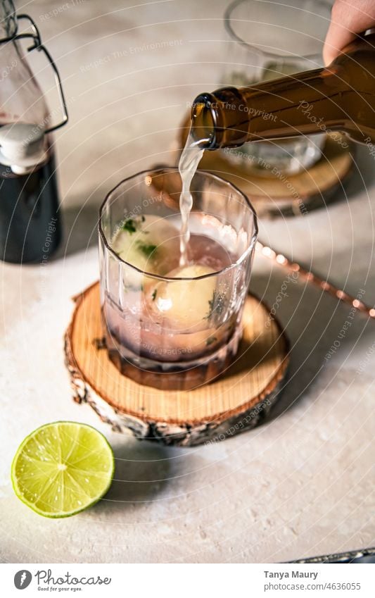 pouring beer in a clear glass cocktail with ice cubes and lime healthy freshness green refreshing refreshment beverage lemonade Bourbon whiskey transparent