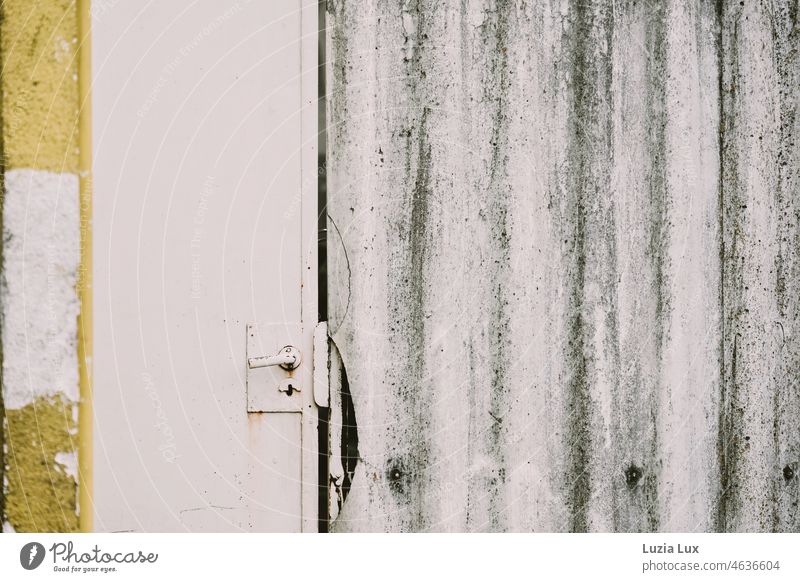 The ravages of time or an old courtyard door in peeling white, the house wall was once bright yellow Facade Door to the courtyard dilapidated Ravages of time