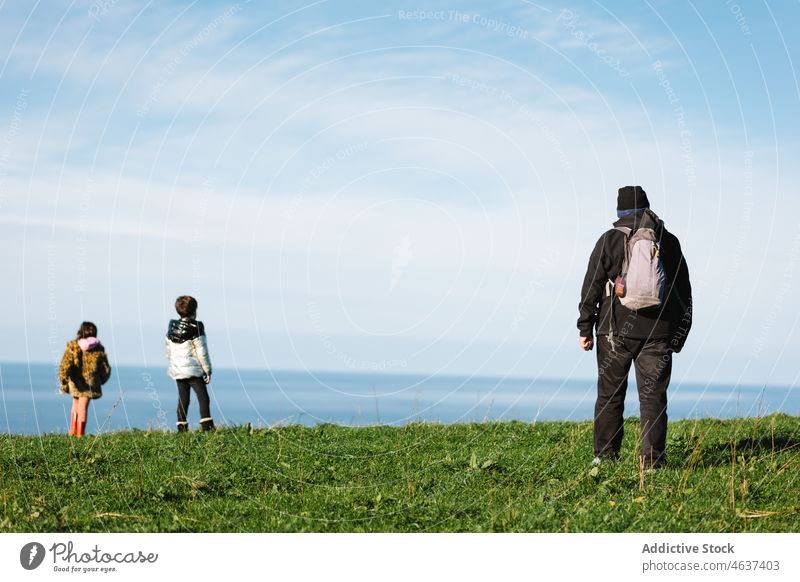 Grandfather and grandkids observing seascape from hill grandparent grandchild grandfather nature explore together admire observe blue attention show grandson