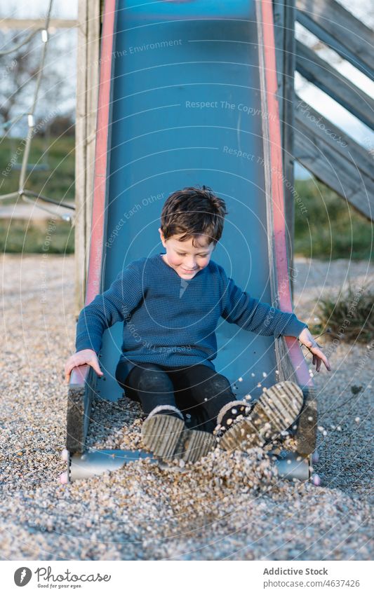 Cute boy sliding on playground kid slide having fun entertain childhood amusement playful summer pastime leisure recreation rest cute innocent lifestyle